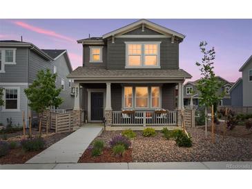 Charming two-story home featuring a welcoming front porch and landscaped front yard at 8057 Monte Vista Cir, Littleton, CO 80125