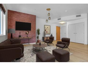 Cozy living room with a brick accent wall, modern furniture, and hardwood floors at 1438 Little Raven St # 201, Denver, CO 80202