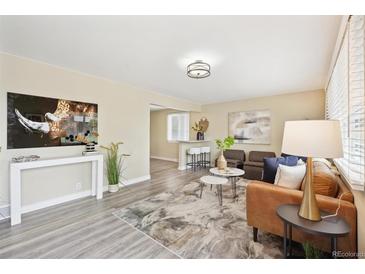 Bright living room featuring light wood flooring, stylish decor, and a cozy seating arrangement at 6953 Elati Way, Denver, CO 80221