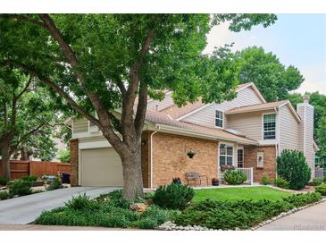 Charming two-story home featuring brick accents, an attached garage, and mature landscaping at 1563 S Trenton Ct, Denver, CO 80231