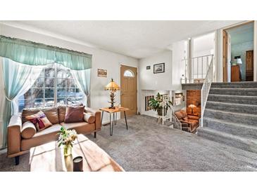 Inviting living room with a large window, a plush sofa, and an open staircase to the second floor at 16505 E Arkansas Ave, Aurora, CO 80017