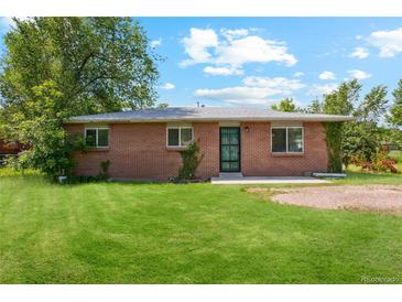 Charming brick home featuring a well-manicured front lawn and mature trees at 1060 Saulsbury St, Lakewood, CO 80214