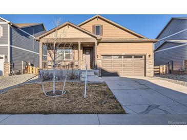 Charming home with a well-manicured lawn, inviting porch, and convenient attached two-car garage at 222 Fox St, Bennett, CO 80102