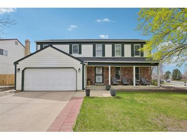 Charming two-story home with an attached garage and a brick porch, set against a vibrant blue sky at 1001 S Nucla St, Aurora, CO 80017