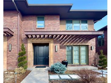 Inviting two-story brick home featuring a pergola covered entrance, professional landscaping, and a walkway to the front door at 318 Adams St, Denver, CO 80206