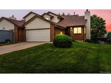 Two-story home with a brick and vinyl exterior, featuring an attached garage and well-maintained lawn at 2040 Yarrow St, Lakewood, CO 80214