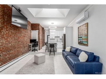 Open living area with exposed brick wall, modern kitchen, and comfortable seating at 2512 Kensing Ct, Denver, CO 80211