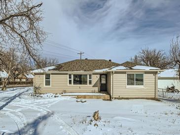 Tan house with dark door, snow covered yard at 8501 E 104Th Ave, Henderson, CO 80640