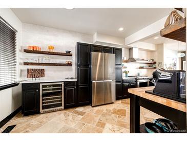 Modern kitchen featuring stainless steel appliances, black cabinets, travertine floors, and floating wood shelves at 3383 Mount Royal Dr # 46, Castle Rock, CO 80104
