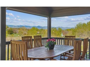 Inviting covered patio with wooden furniture and mountain views, perfect for outdoor dining and relaxation at 9531 Desert Willow Way, Highlands Ranch, CO 80129