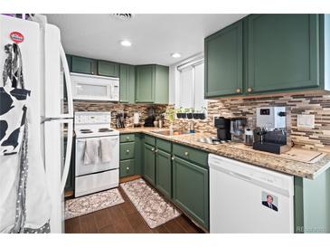Cozy kitchen features green cabinets, mosaic tile backsplash, and granite countertops at 970 S Dawson Way # 9, Aurora, CO 80012
