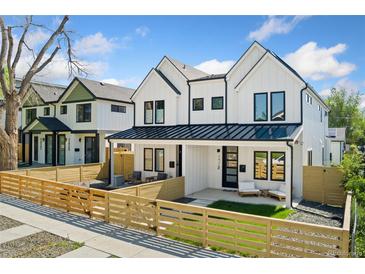 Charming two-story home featuring white siding, black accents, and a well-maintained front yard with a wooden fence at 2426 Ames St, Edgewater, CO 80214