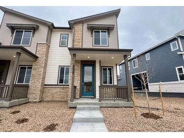 Charming two-story townhome featuring stone accents, a covered porch, and a well-maintained front yard at 6658 N Nepal Ct, Aurora, CO 80019