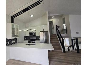 Modern kitchen with stainless steel appliances, white cabinets, and a large island with pendant lighting at 17605 E Temple Dr, Aurora, CO 80015