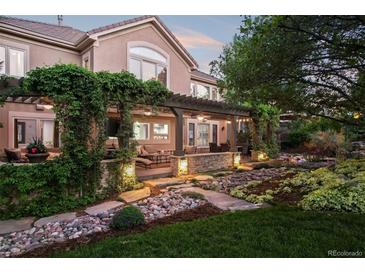 Wonderful outdoor patio area with stone features, pergola, and mature landscaping at 1102 Buffalo Ridge Rd, Castle Pines, CO 80108