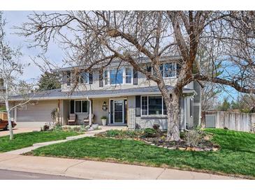 Charming two-story home with manicured lawn and inviting front porch, perfect for enjoying the outdoors at 8029 W Hoover Pl, Littleton, CO 80123