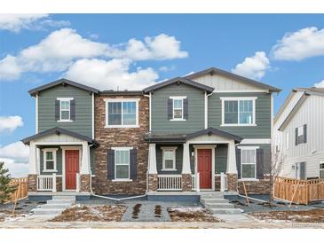 Two-story townhome with gray siding, stone accents, and red doors at 20690 E 58Th Ave, Aurora, CO 80019