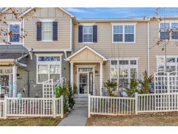 Inviting two-story townhouse with neutral siding, dark shutters, and charming white picket fence in front at 1465 Red Cliff Way, Castle Rock, CO 80109