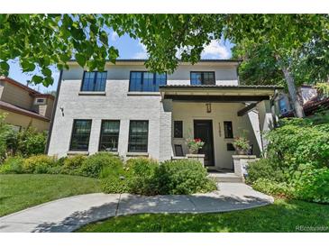 Charming two-story home with a white brick exterior and landscaped front yard with black window frames at 1265 S Gaylord St, Denver, CO 80210