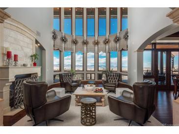 Sunlit living room with high ceilings, floor-to-ceiling windows, fireplace, and mountain views at 8871 Aspen Leaf Ct, Littleton, CO 80125