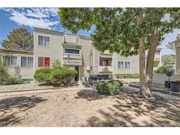 Exterior of a multi-Gathering unit with a small patio, grill, and light-yellow siding surrounded by bushes and trees at 10752 E Exposition Ave # 332, Aurora, CO 80012