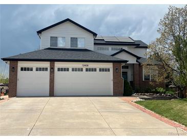 Charming two-story home with a three-car garage, brick accents, solar panels, and manicured landscaping at 12408 W 83Rd Ave, Arvada, CO 80005