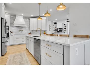 Bright, white kitchen featuring a large island with quartz countertops and gold hardware at 12408 W 83Rd Ave, Arvada, CO 80005