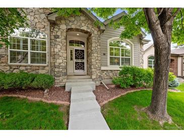 Charming home featuring a stone facade, arched entry, and well-maintained landscaping at 6900 W Grant Ranch Blvd # 88, Denver, CO 80123