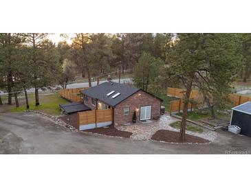 Charming brick home with a well-maintained yard, updated fence and stone patio surrounded by mature trees at 34480 County Road 17, Elizabeth, CO 80107