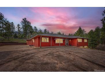 Stunning exterior of red home with inviting front yard and beautiful sunset sky in the background at 4776 Red Rock Dr, Larkspur, CO 80118