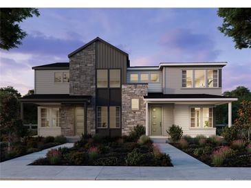 Modern two-story townhome featuring stone accents, covered porches, and professionally landscaped front yard at 8900 Yellowcress St, Littleton, CO 80125