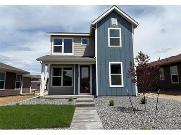 Charming two-story home with blue and grey siding and well-maintained front yard at 2303 Peregrine Dr, Brighton, CO 80601