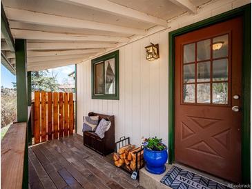 Charming front porch with wood floors, a cozy bench, and a decorative front door at 2733 S Riverview Dr, Idledale, CO 80453