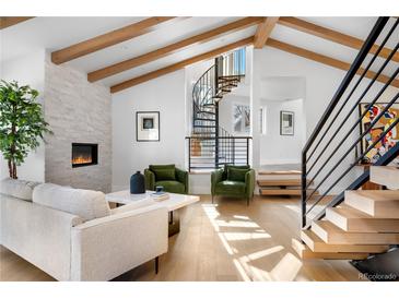Bright living room with fireplace, hardwood floors, beamed ceilings, and spiral staircase at 245 Fair Pl, Boulder, CO 80302