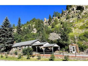 Charming stone and wood home nestled in a mountain setting with a covered porch and lush greenery at 4364 Colorado 103, Idaho Springs, CO 80452