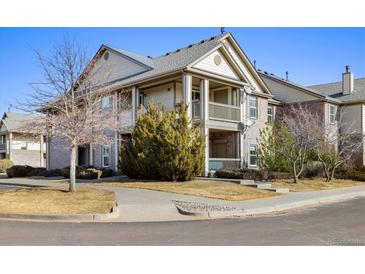 Charming condo featuring a brick and beige exterior, complimented by a cozy covered balcony and lush green landscaping at 23405 E 5Th Pl # 201, Aurora, CO 80018