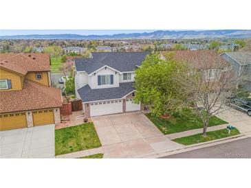 Traditional two-story home featuring a large driveway and well-maintained lawn and landscaping at 6614 W Gould Dr, Littleton, CO 80123