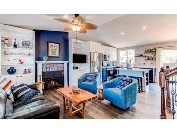 Cozy living room featuring a fireplace, plush armchairs, and an open kitchen concept at 8463 Wheatgrass Cir, Parker, CO 80134