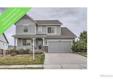 Charming two-story home featuring a well-manicured lawn, stone accents, and an attached two-car garage at 8695 Torrey St, Arvada, CO 80007