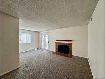 Inviting living room featuring a cozy fireplace and sliding door access to the outdoor space at 12470 E Cornell Ave # 203, Aurora, CO 80014