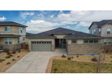 Charming single-story home with a well-manicured lawn and a stone-accented facade at 19409 W 88Th Dr, Arvada, CO 80007