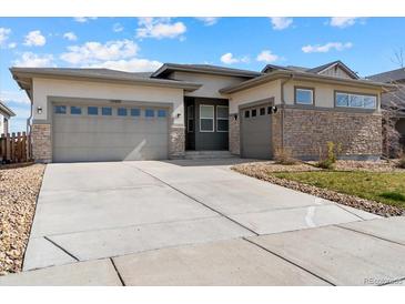 Charming stucco and stone home featuring a large driveway and three-car garage at 19409 W 88Th Dr, Arvada, CO 80007