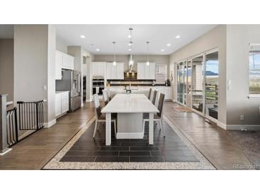 Bright, open kitchen features white cabinets, stainless steel appliances and a spacious island with seating at 19409 W 88Th Dr, Arvada, CO 80007