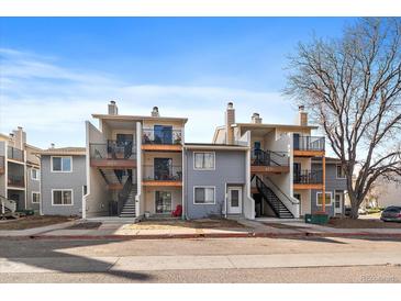 Two-story townhome featuring a private balcony, grey siding, and well-maintained front yard landscaping at 6011 Yarrow St # C, Arvada, CO 80004