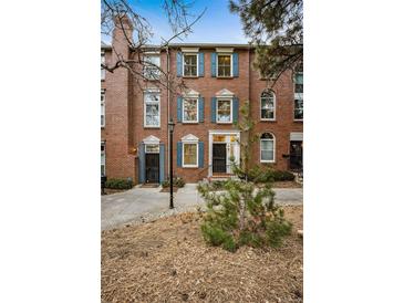 Charming brick townhome featuring blue shutters, a landscaped front yard, and a welcoming entrance at 479 Josephine St, Denver, CO 80206