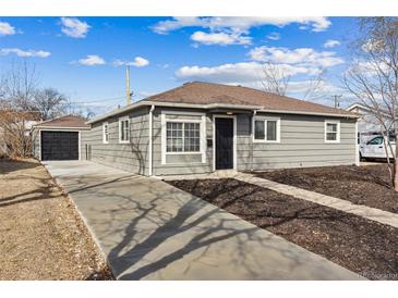 Charming single-story home with a long driveway and detached garage under a partly cloudy blue sky at 1227 Yost St, Aurora, CO 80011