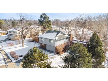 Charming two-story home with attached garage, nestled among mature trees and a snow-covered landscape at 6378 S Benton Way, Littleton, CO 80123