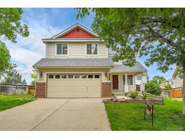 Charming two-story home with a two-car garage, red accents, and a well-manicured front yard at 5023 Goshawk Ct, Brighton, CO 80601