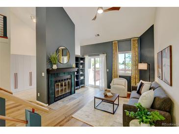 Inviting living room features a fireplace, hardwood floors, a ceiling fan and a sliding glass door to the deck at 11358 W 85Th Pl # E, Arvada, CO 80005