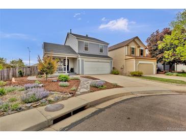 Two-story home with charming curb appeal, a front porch, a two-car garage, and colorful landscaping at 14430 W Yale Pl, Lakewood, CO 80228